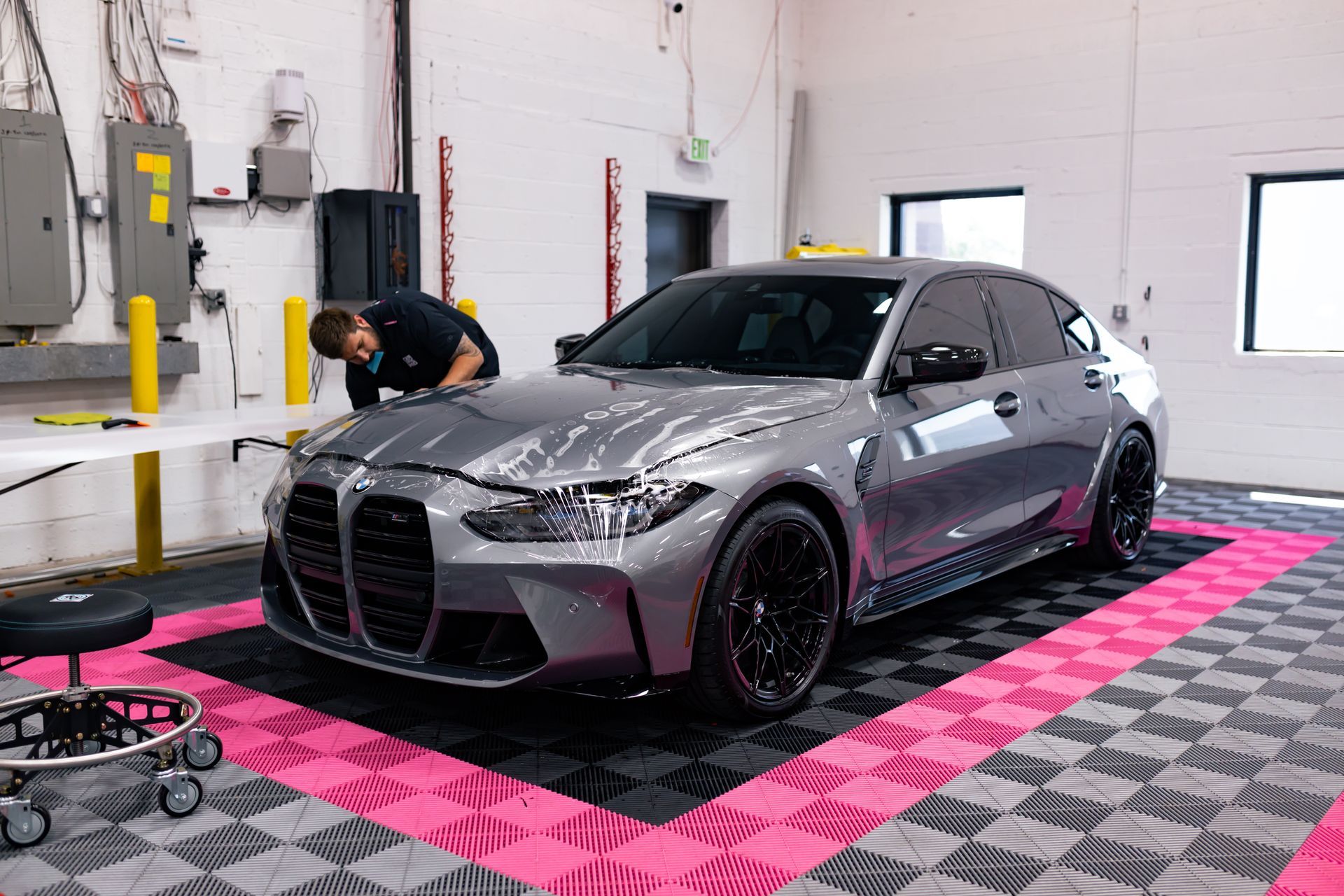 A man is working on a bmw m3 in a garage.