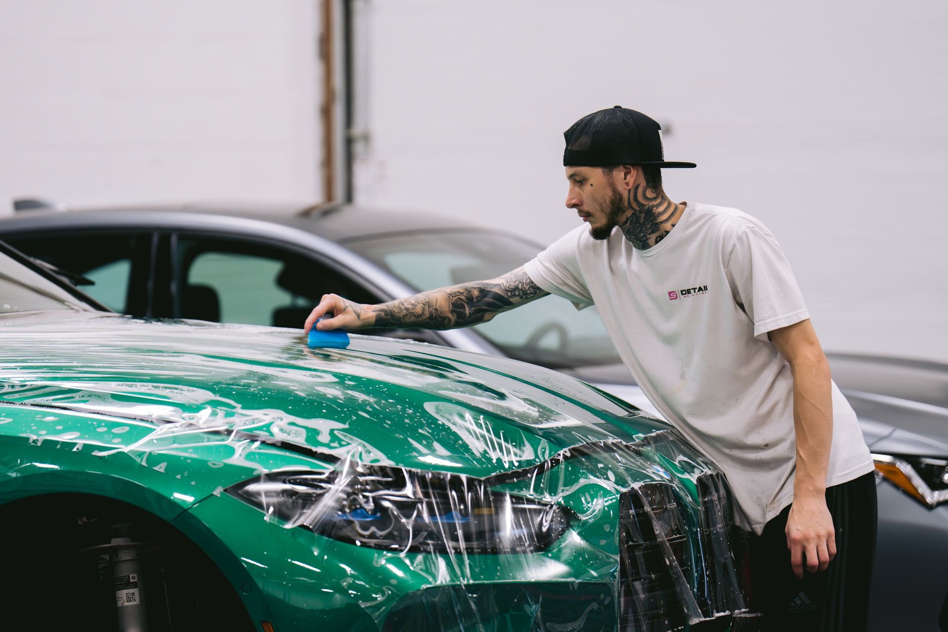 A man is wrapping a car with plastic wrap.