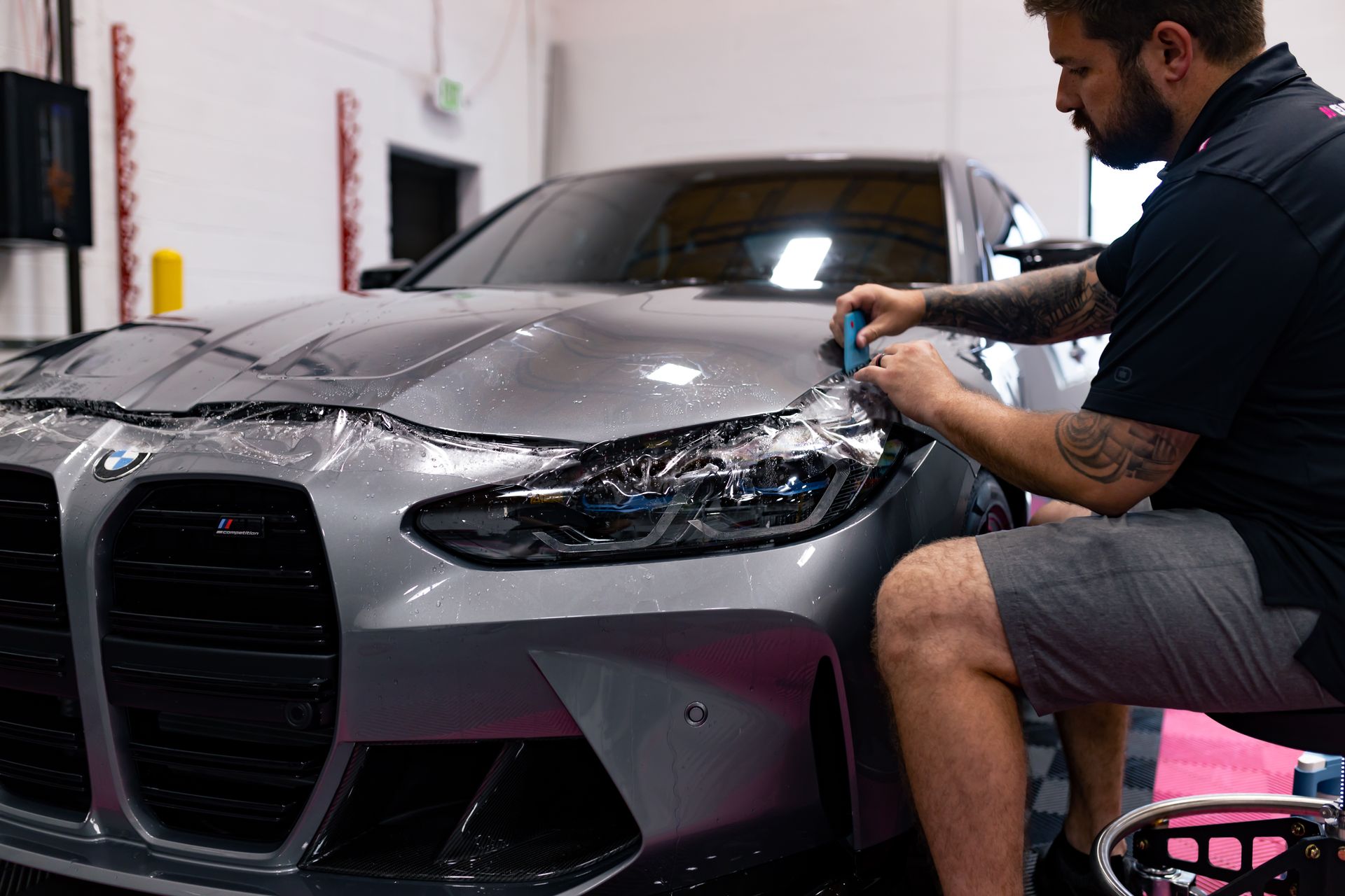 A man is wrapping a car with plastic wrap.