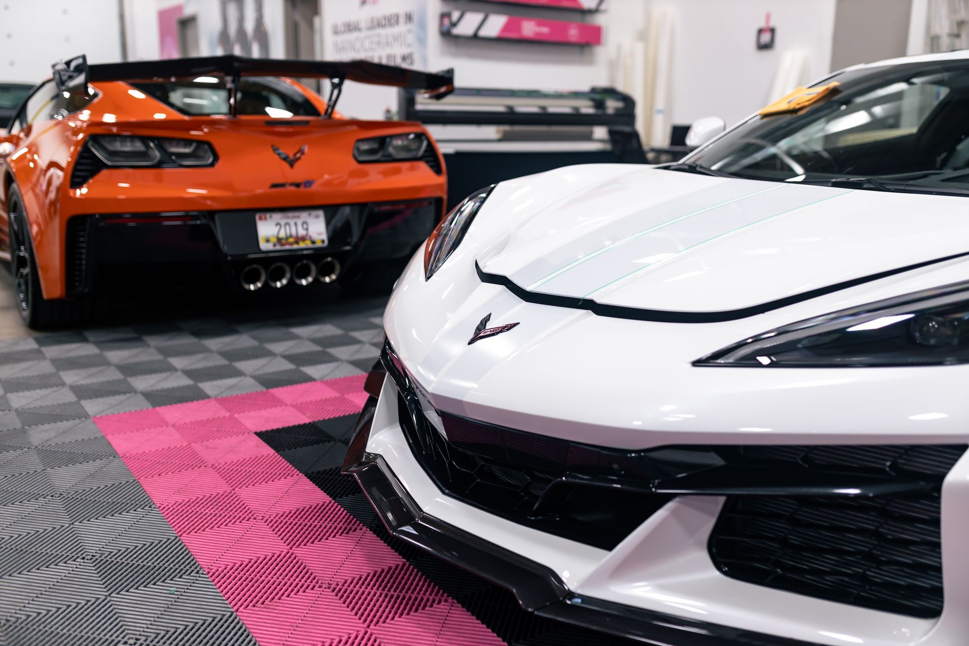 Two sports cars are parked next to each other in a garage.