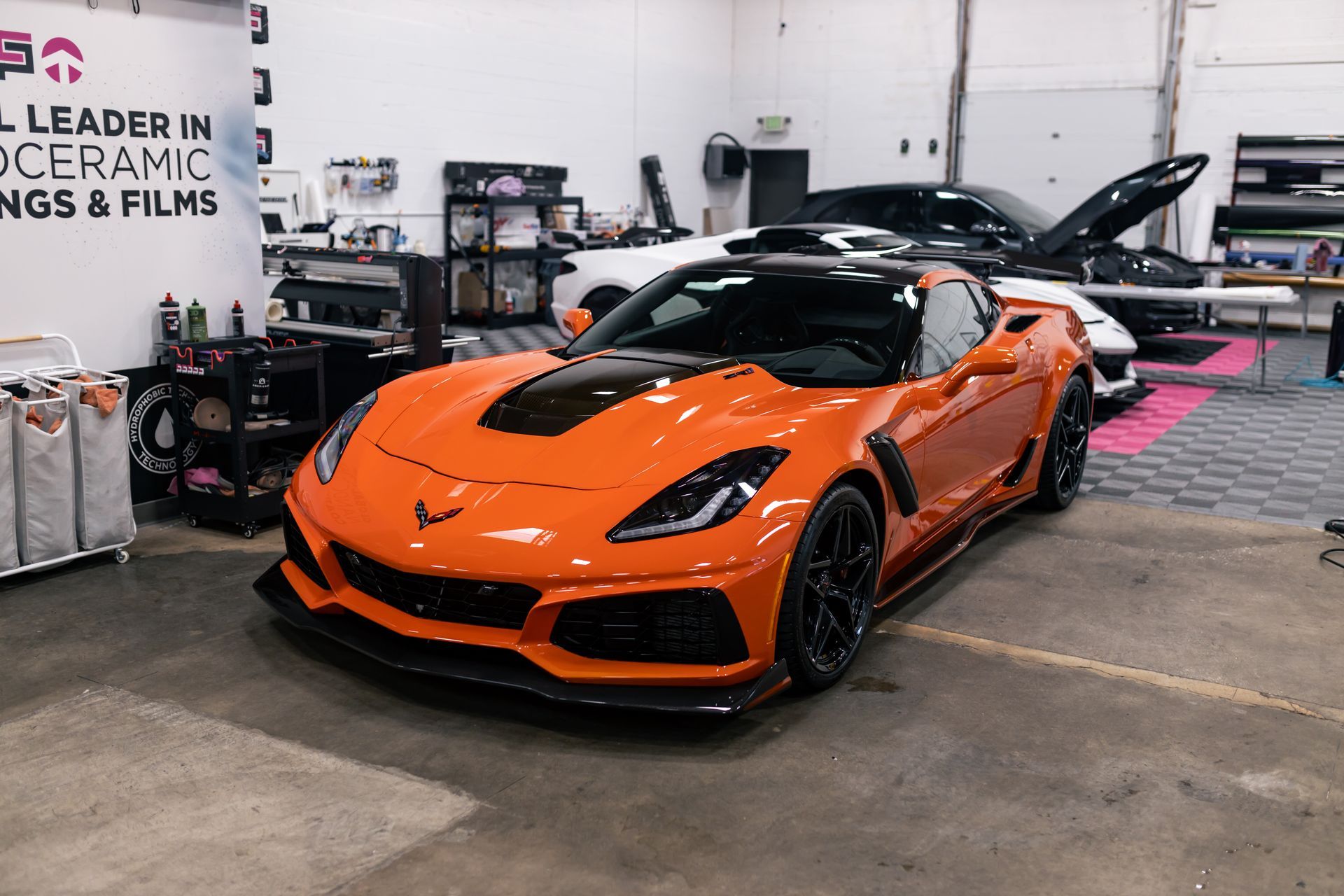 An orange corvette zr1 is parked in a garage.