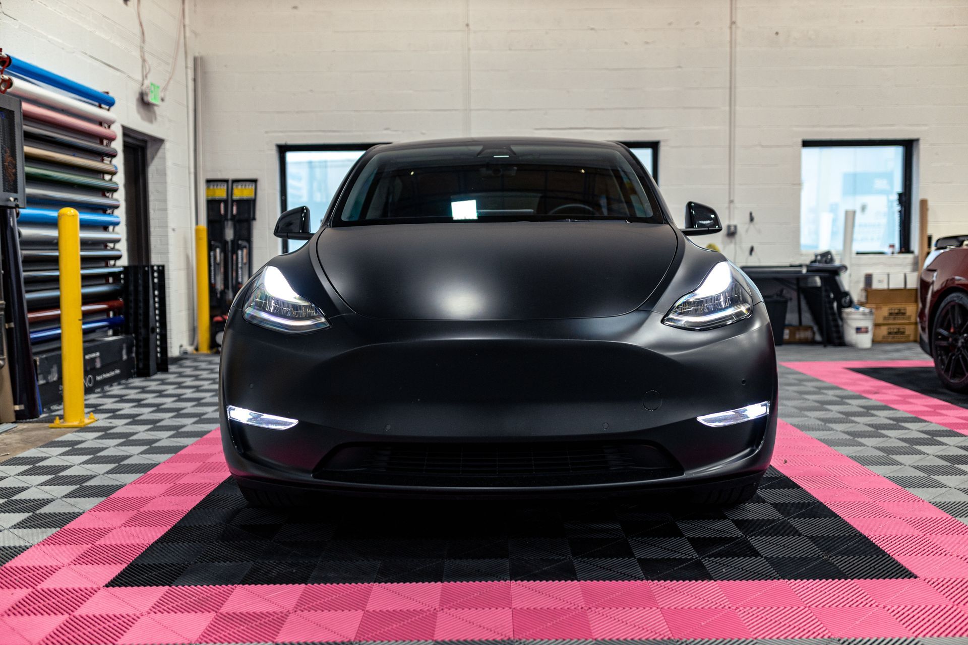 A black tesla model 3 is parked in a garage.