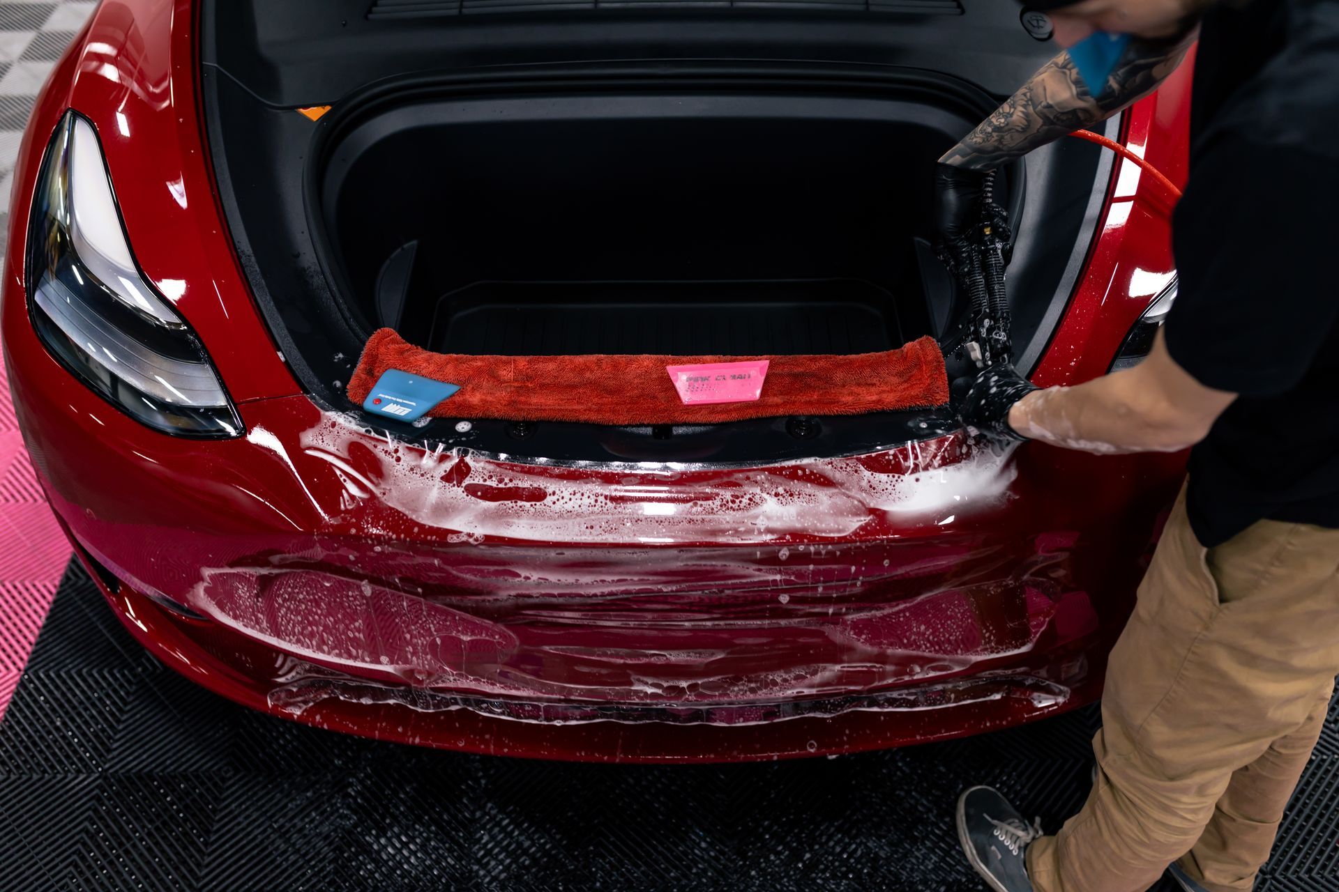 A person is applying protective film to the hood of a car.