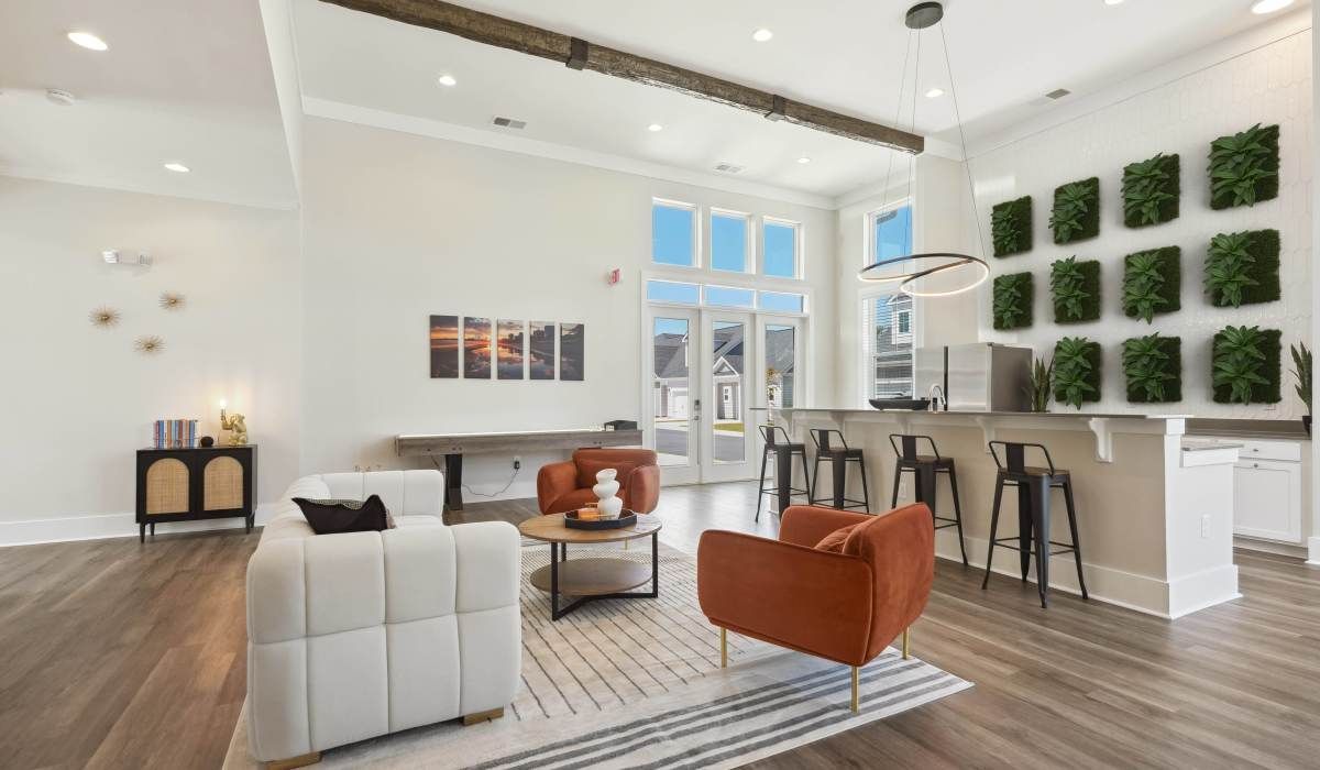 Modern lounge area with seating, bar, and green wall.