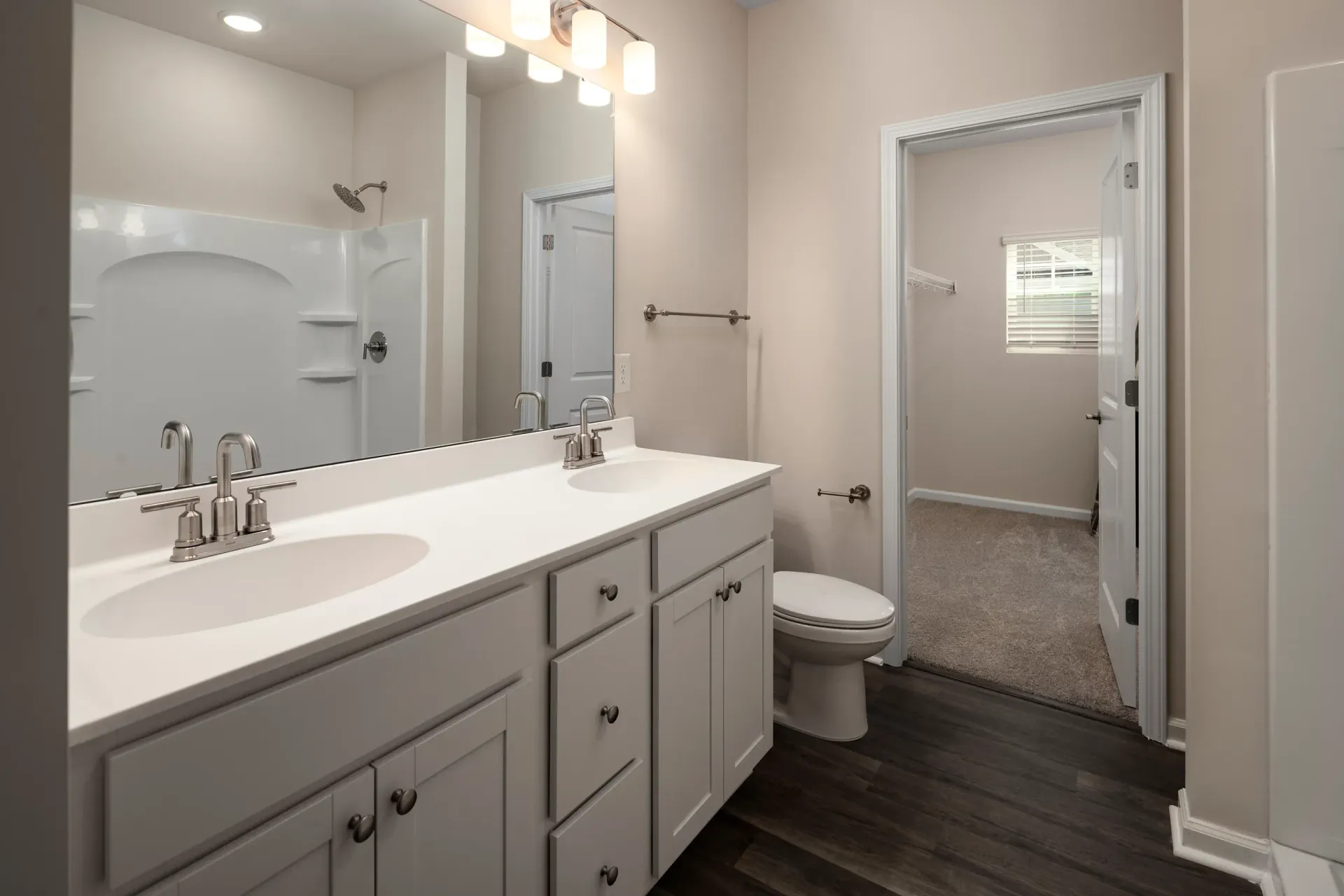 Bathroom with a double-sink vanity, toilet, and shower-tub combo.