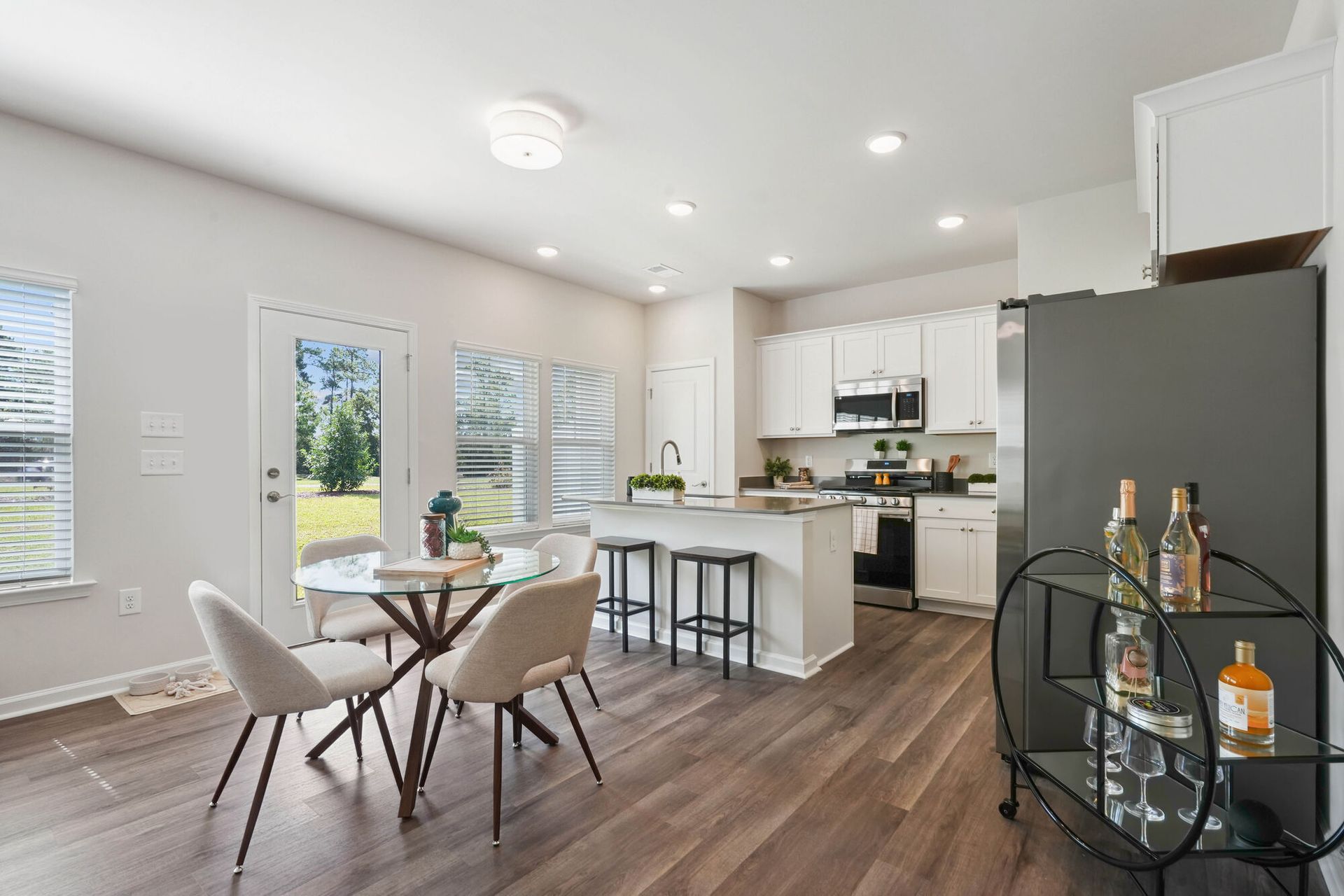 Open-concept kitchen and dining area with island, white cabinets, and stainless appliances.