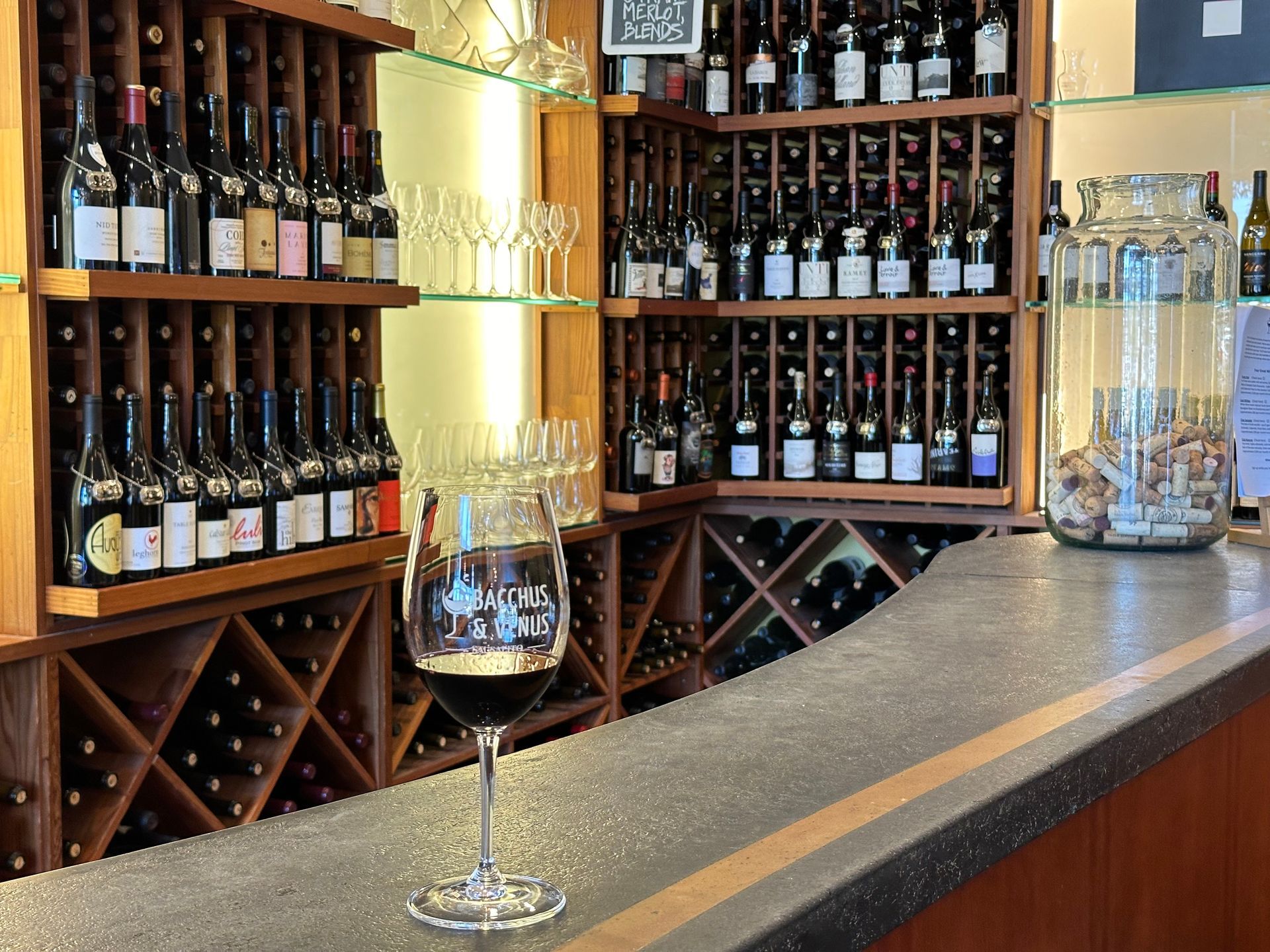 A glass of wine is sitting on a bar in a wine cellar.