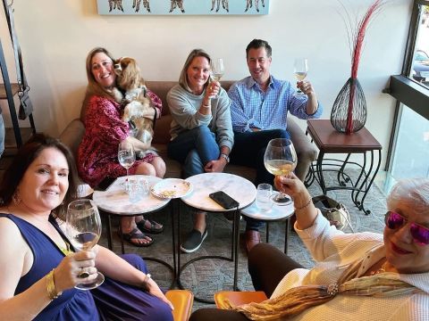 A group of people are sitting on a couch holding wine glasses.