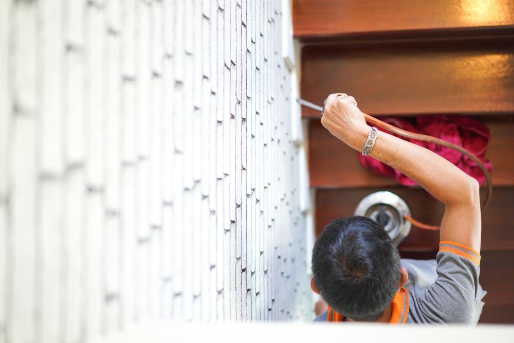 A Man Is Painting A Wall With A Brush — ASAP Pest Control in Logan, QLD