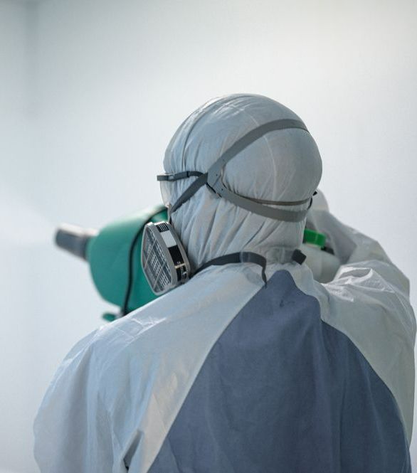 A Person Wearing A Protective Suit And Mask Is Spraying Something — ASAP Pest Control in Carindale, QLD