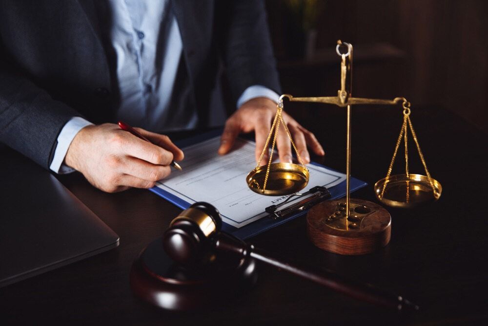 A Lawyer Is Sitting At A Desk With A Scale Of Justice And A Gavel — ASAP Pest Control in Yeerongpilly, QLD