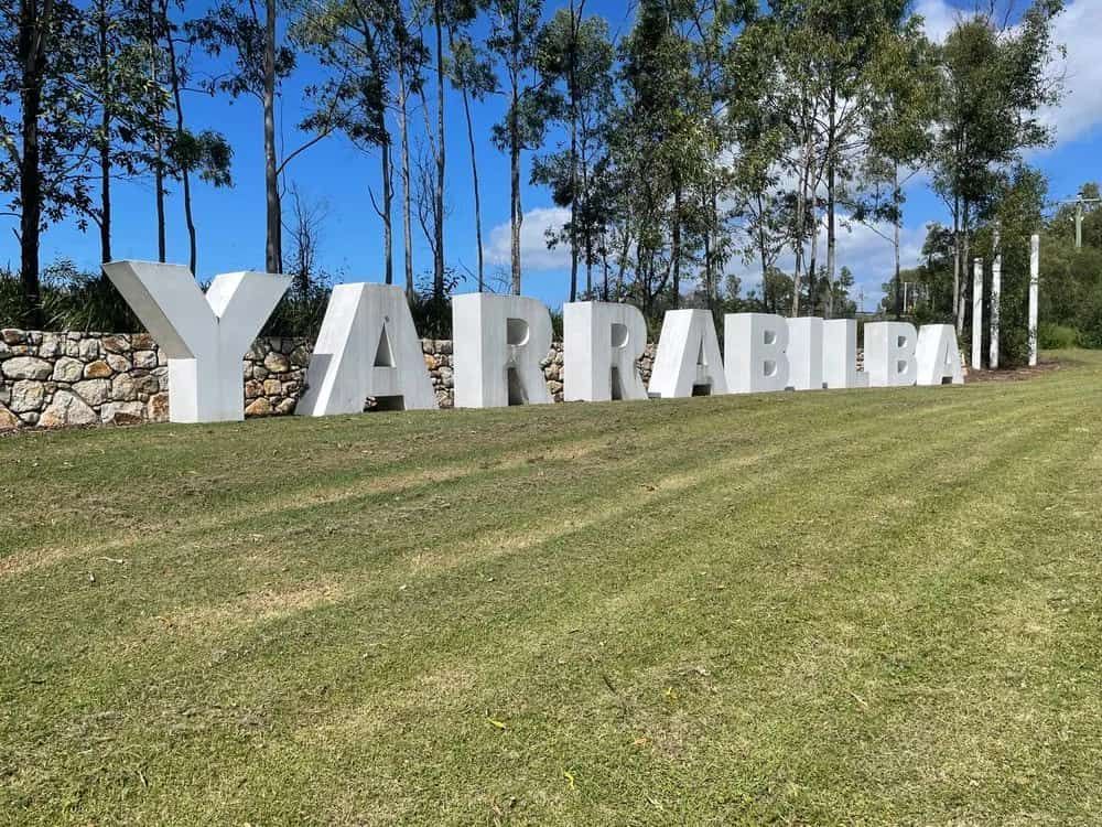 A Large Sign That Says Yarrabilla Is In The Middle Of A Grassy Field — ASAP Pest Control in Logan, QLD