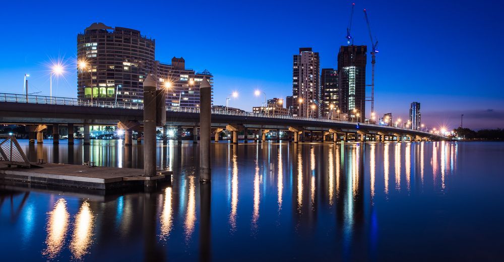 A Bridge Over A Body Of Water With A City In The Background At Night — ASAP Pest Control in Gold Coast, QLD