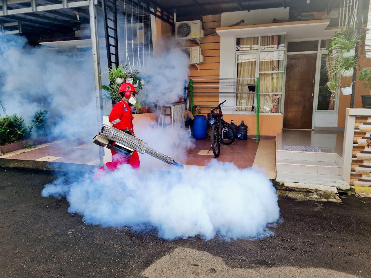 A Man Is Spraying Smoke In Front Of A House — ASAP Pest Control in Tamborine, QLD