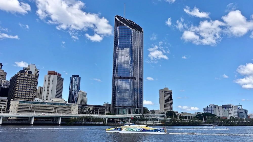 A Boat Is Floating On A River In Front Of A City Skyline — ASAP Pest Control in Brisbane, QLD