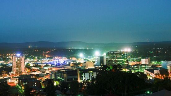 An Aerial View Of A City At Night With Mountains — ASAP Pest Control in Ipswich, QLD