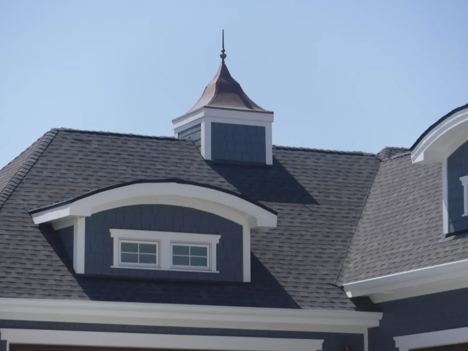 Blue roof with dormer windows and a copper-topped turret against a clear sky.