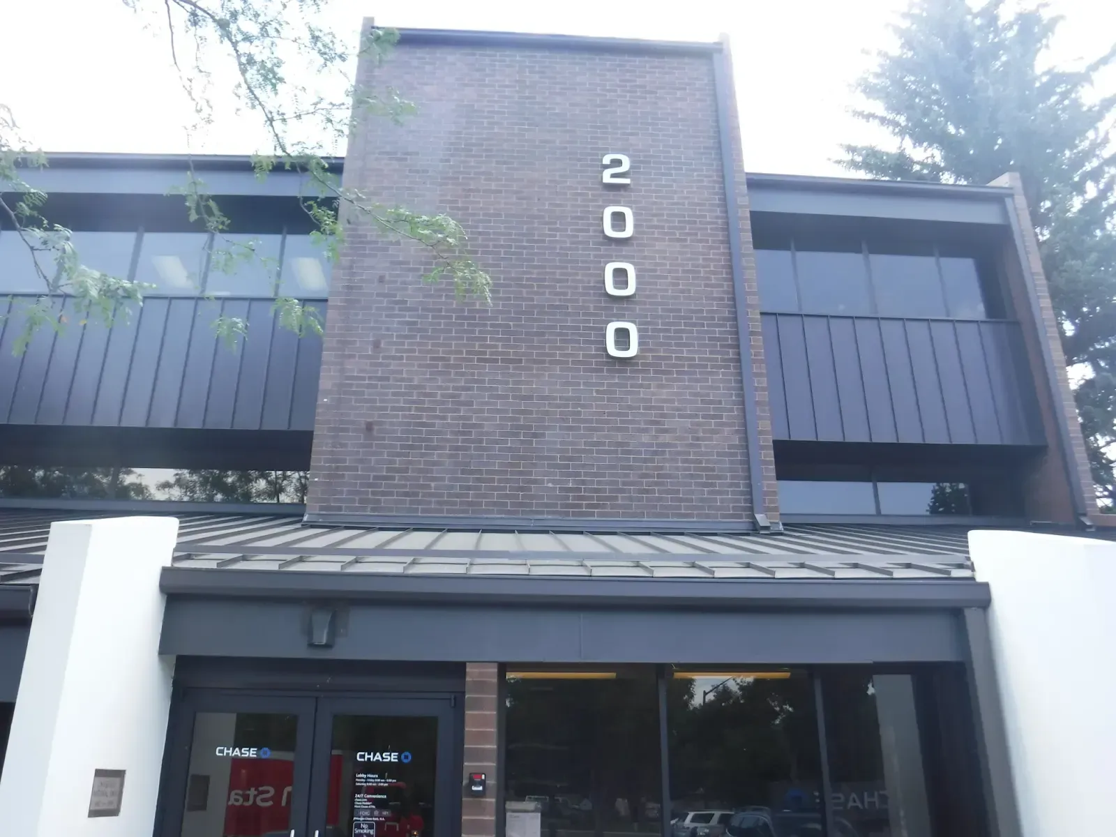 Building with address 2000 in white numbers on a brick facade, dark windows, and a black awning.