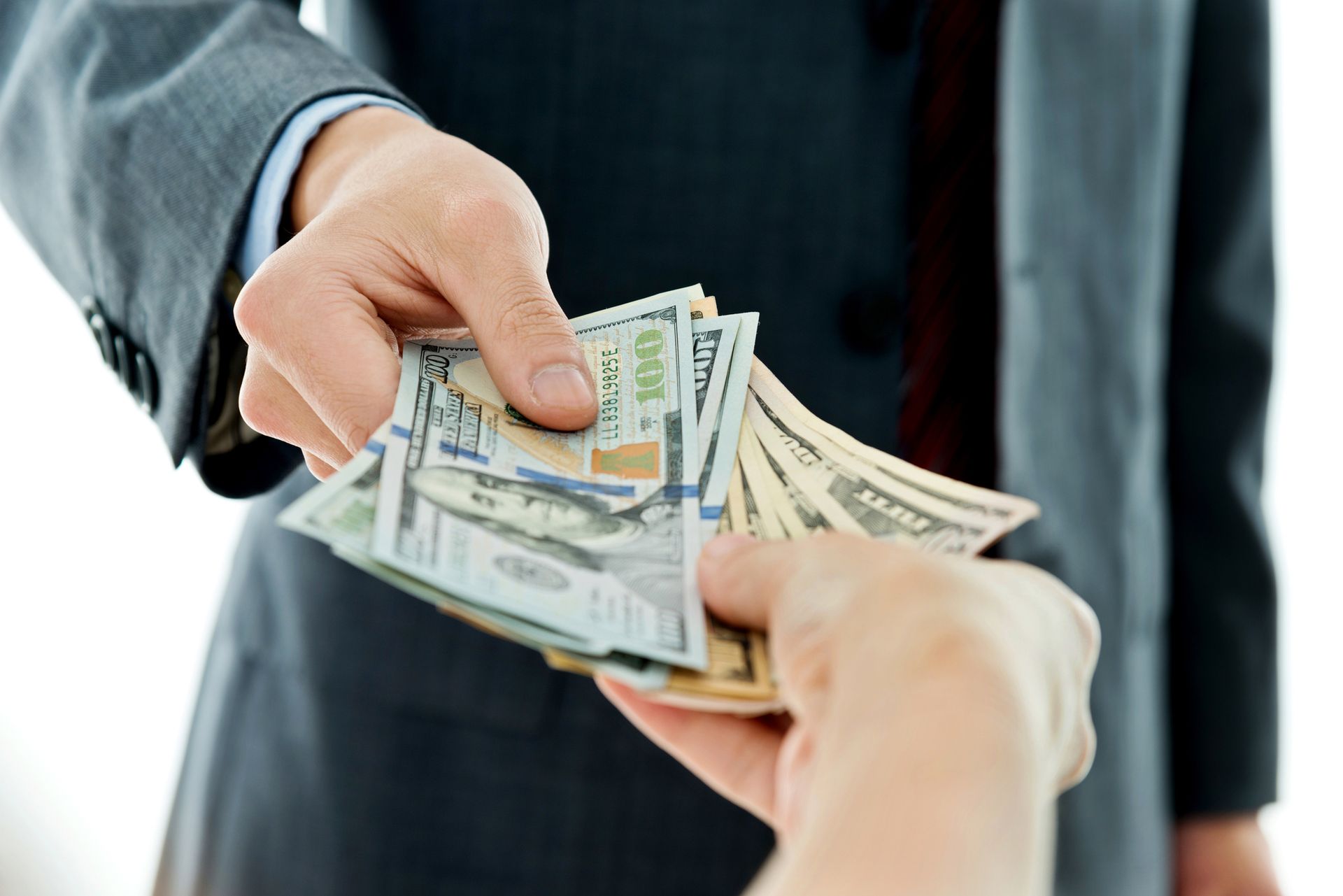 Close-up of businessman's hands giving money.