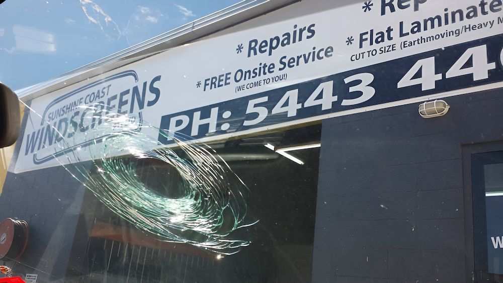 A Windshield With a Broken Glass and a Sign That Says Repairs Flat Laminate — Sunshine Coast Windscreens In Caloundra, QLD