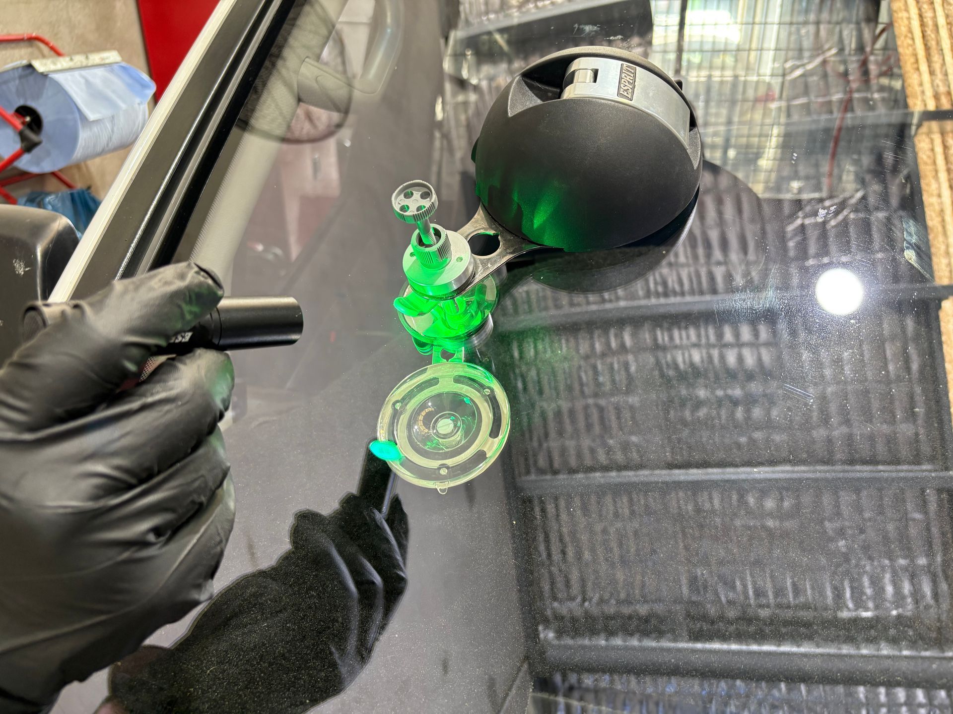 A person wearing black gloves is working on a windshield.