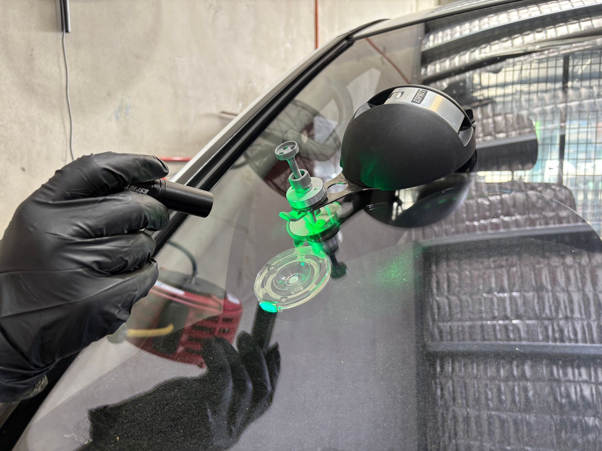 A person wearing black gloves is fixing a windshield on a car.
