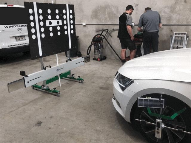 A White Car is Being Aligned in a Garage — Sunshine Coast Windscreens In Buderim, QLD