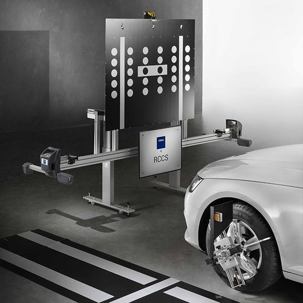 A white car is being adjusted by a machine in a garage.