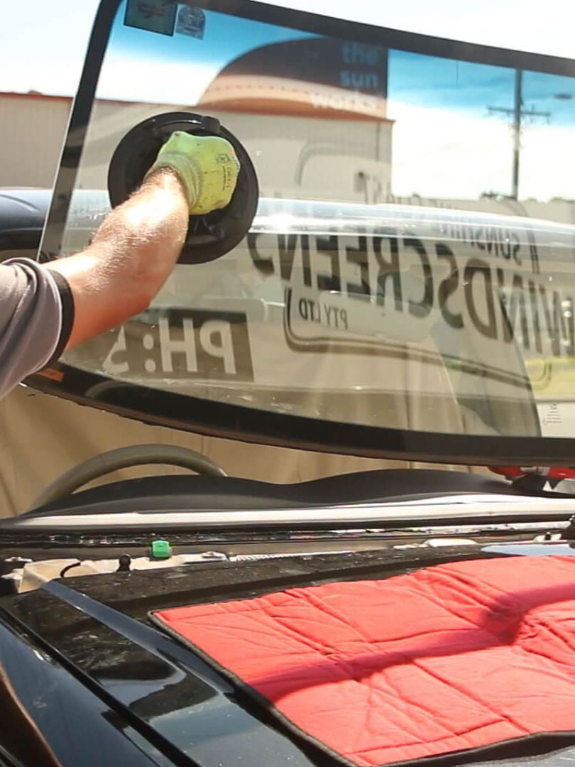 A Person is Cleaning the Windshield of a Car With a Glove — Sunshine Coast Windscreens In Buderim, QLD