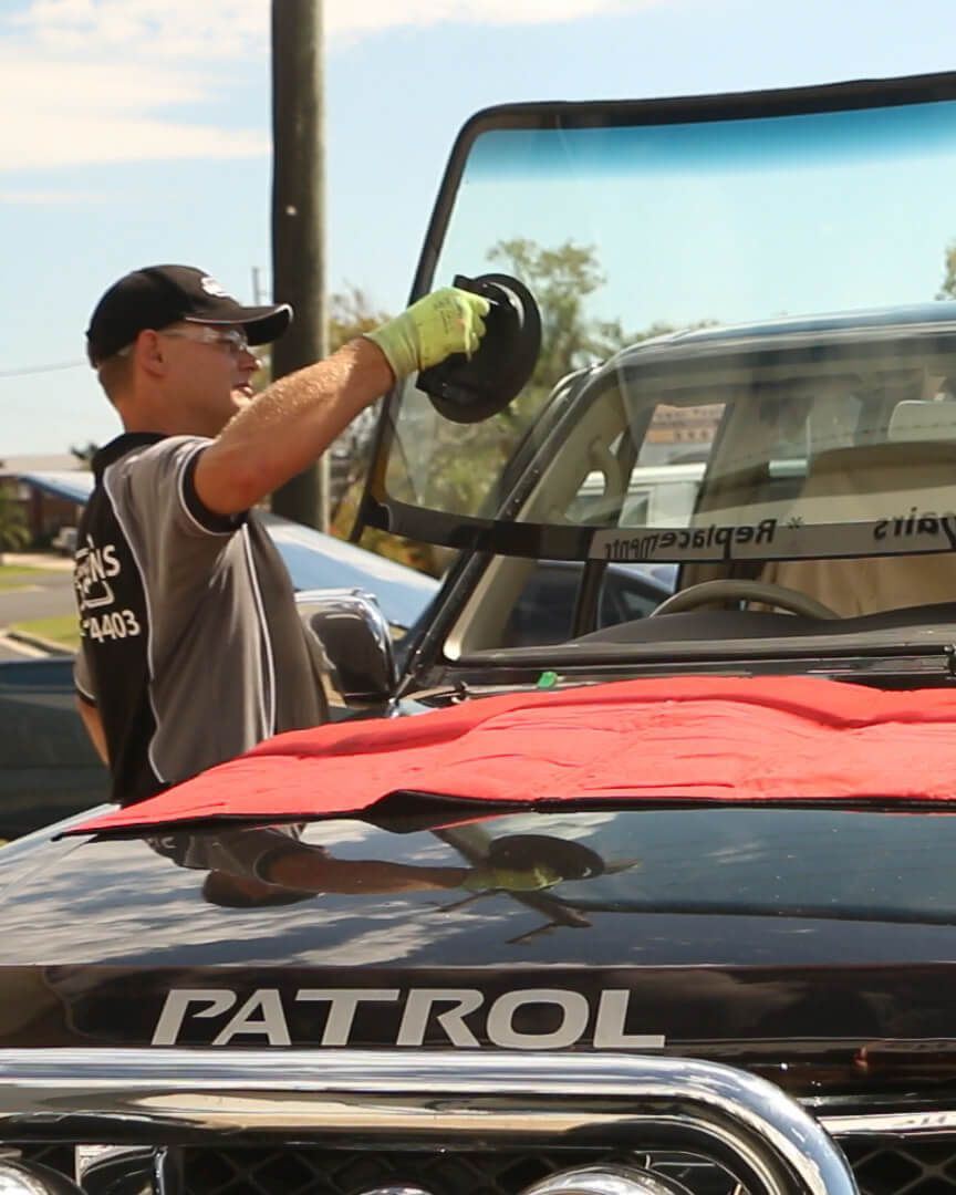 A Man is Working on the Windshield of a Patrol Vehicle — Sunshine Coast Windscreens In Buderim, QLD
