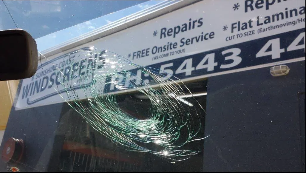 A broken windshield with a sign that says repairs flat lamina