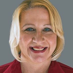 A woman in a red shirt is smiling for the camera.