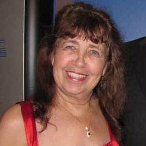 lucile harrington A woman in a red dress and necklace is smiling for the camera.