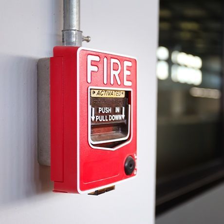 A red fire alarm is mounted on a white wall