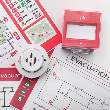 A smoke detector is sitting on top of an evacuation plan.