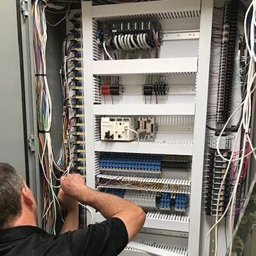 A man is working on a very large electrical box.