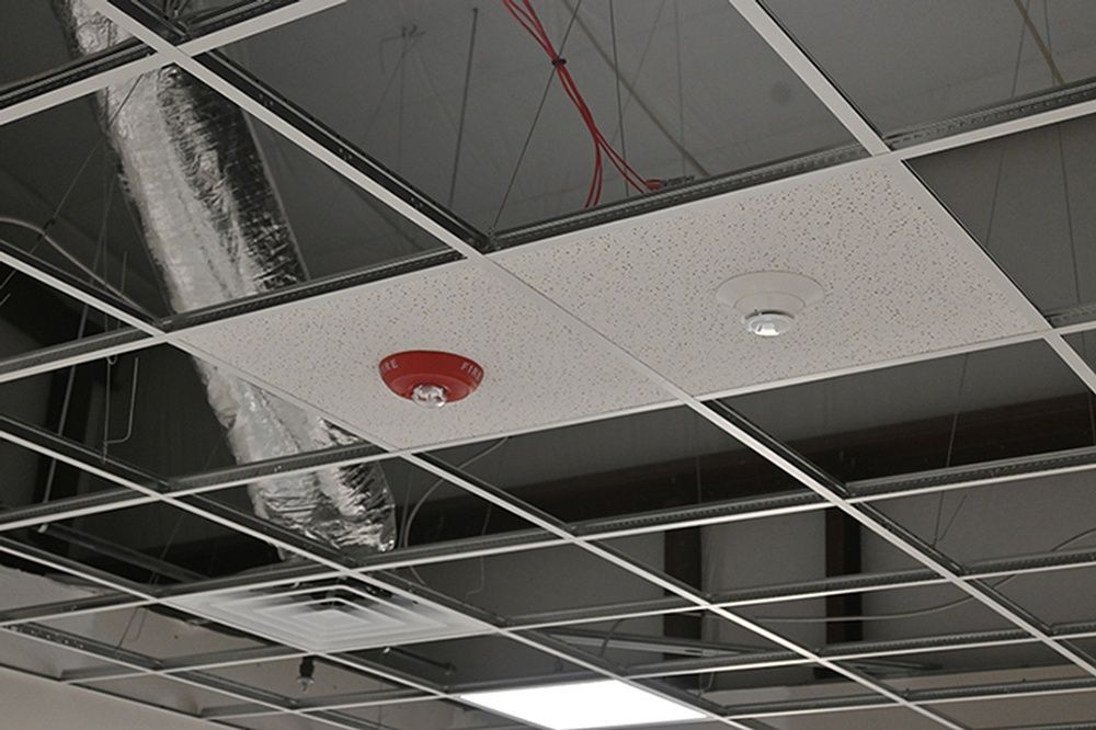 A fire alarm is hanging from the ceiling of a building.
