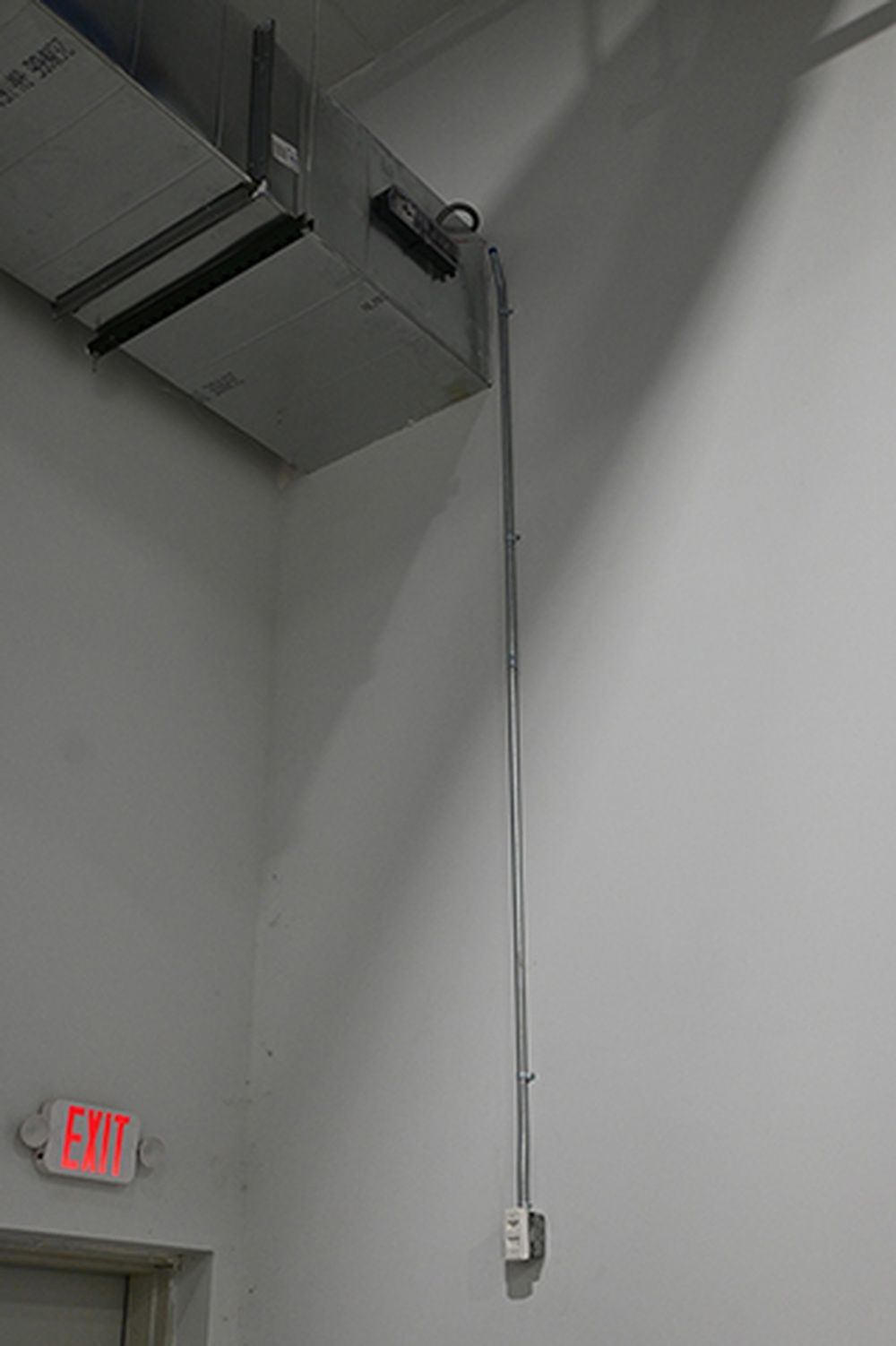 There is a red exit sign on the wall next to a ceiling fan.