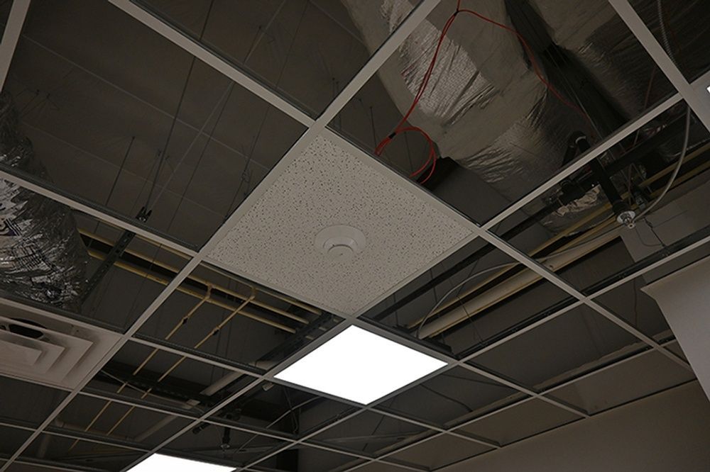 A ceiling with a lot of wires hanging from it and a smoke detector.