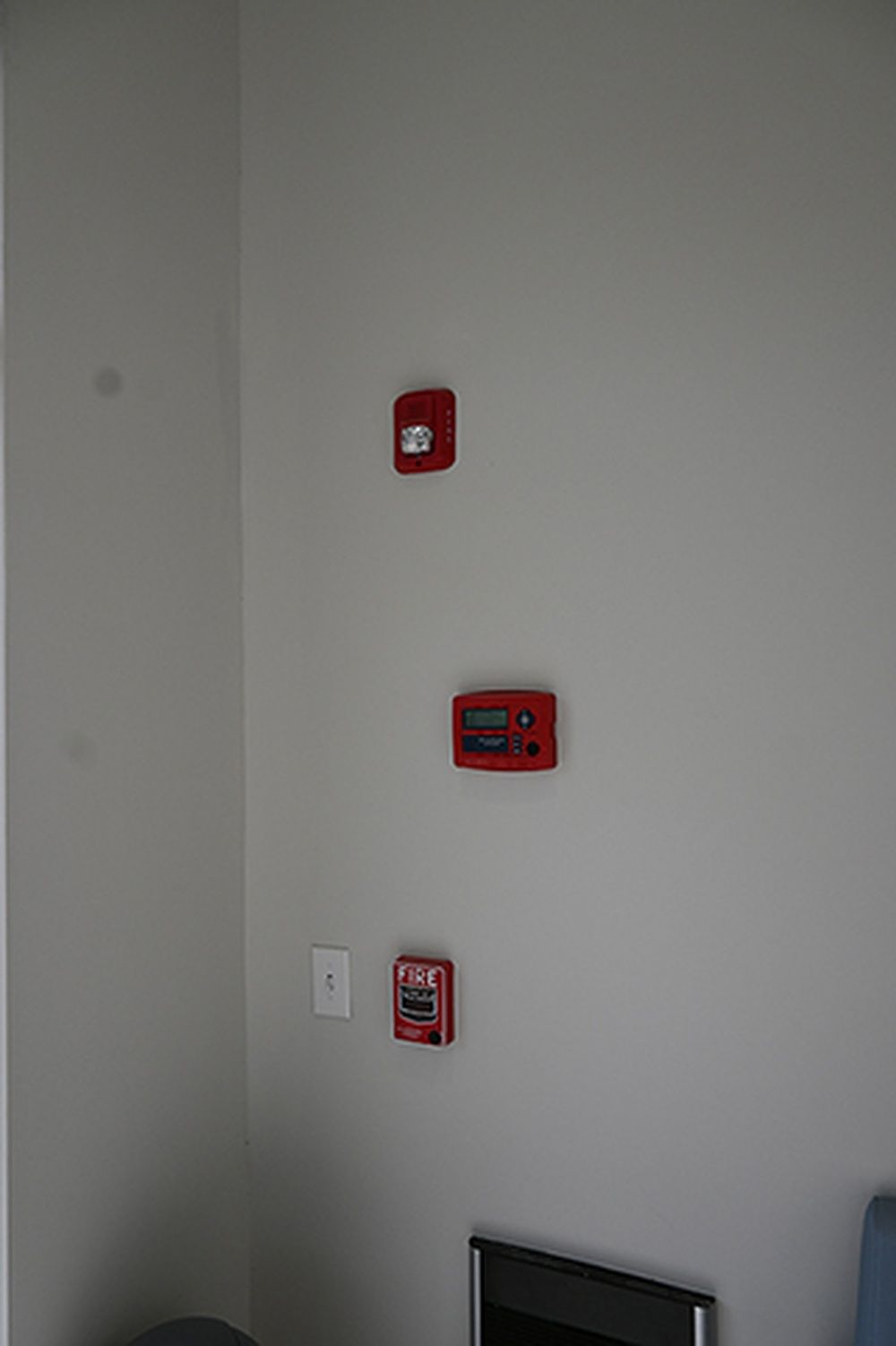 There are three red fire alarms on the wall in a room.