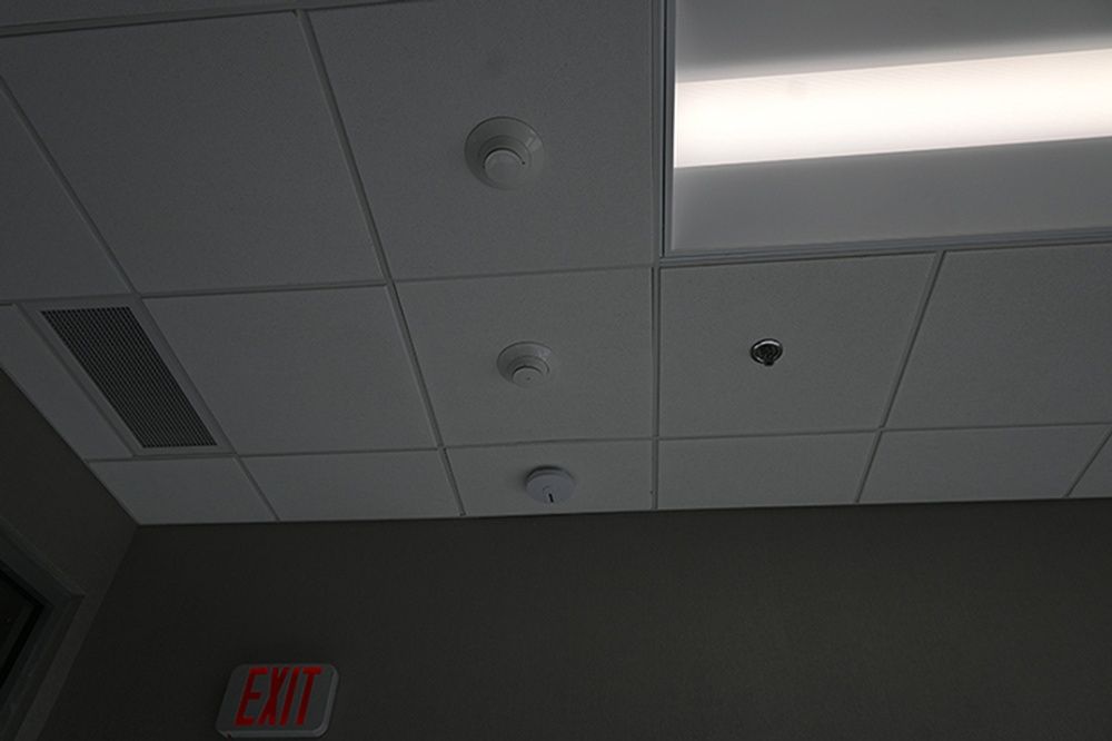 A ceiling with smoke detectors and an exit sign.