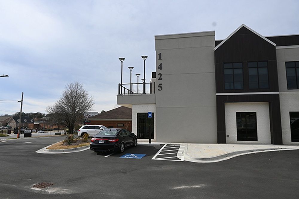 A car is parked in a handicapped parking spot in front of a building.