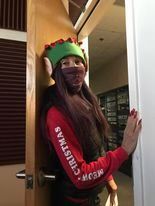A woman in a christmas elf costume is standing in a doorway.