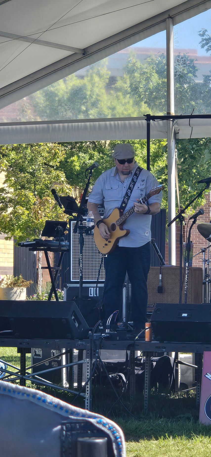 A man is playing a guitar on a stage under a tent.