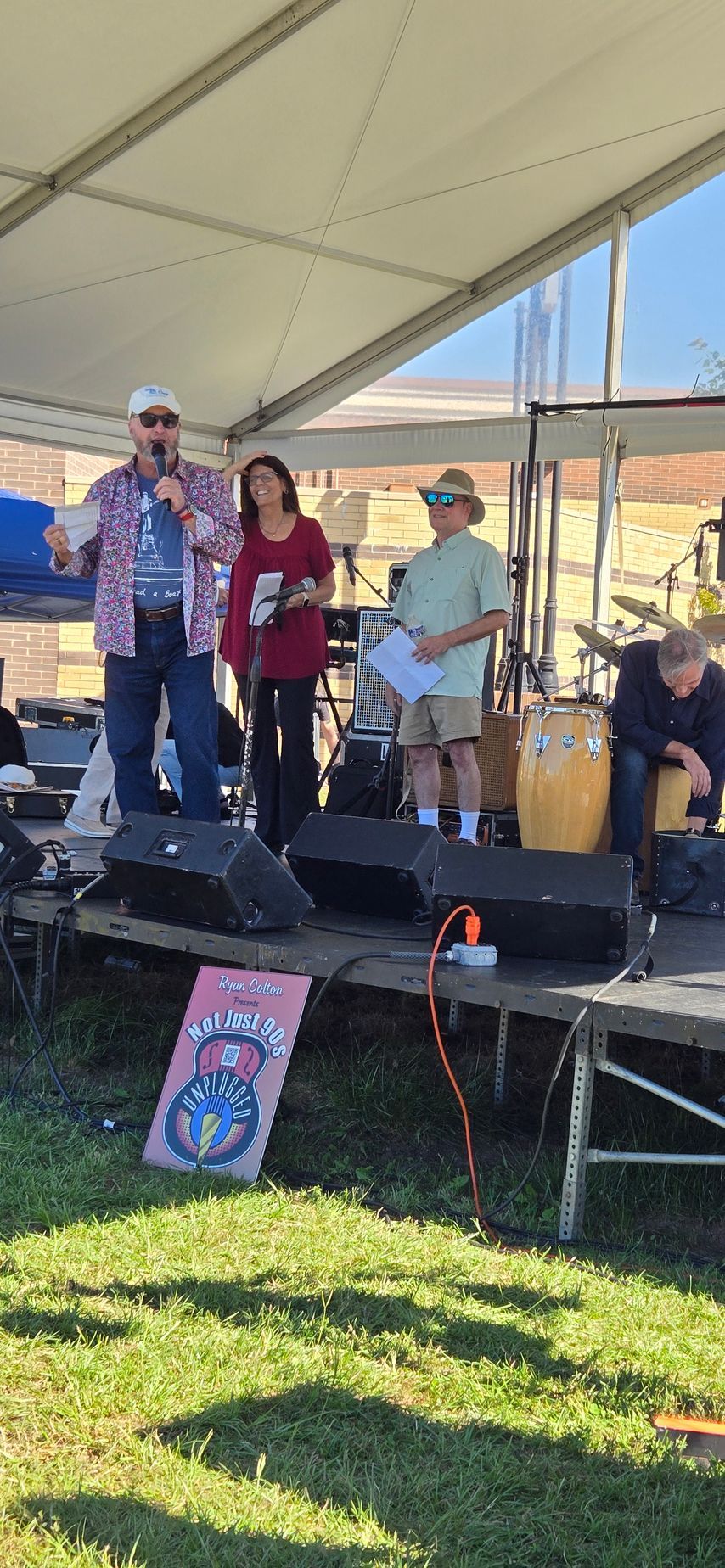 A group of people are standing on a stage under a tent.