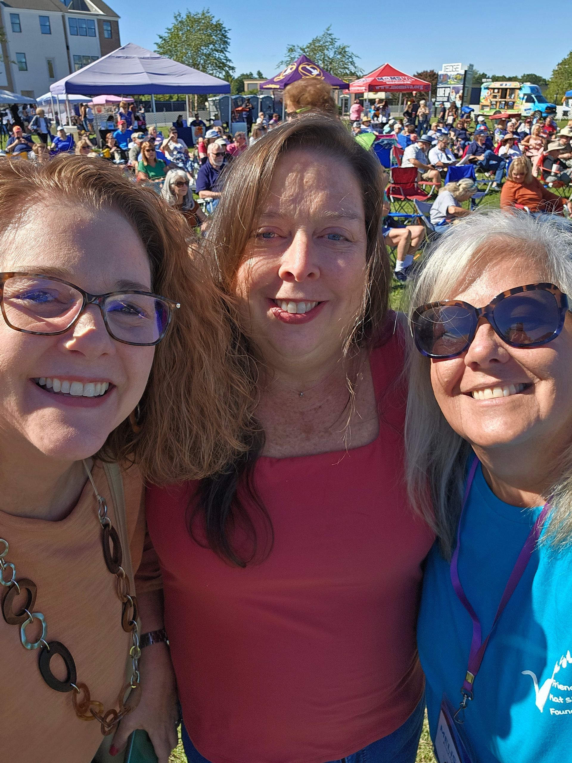 Three women are posing for a picture together at a festival.