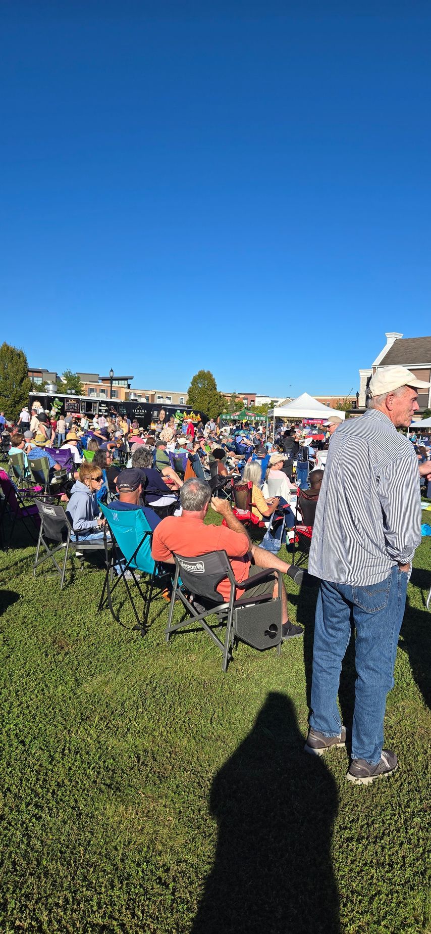 A large group of people are sitting in chairs in a grassy field.