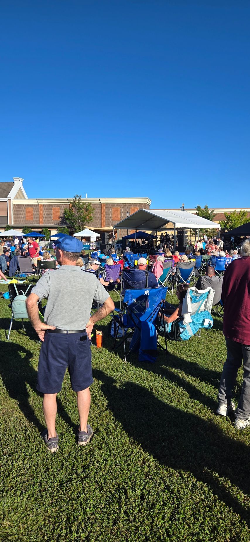 A man is standing in the grass in front of a crowd of people.