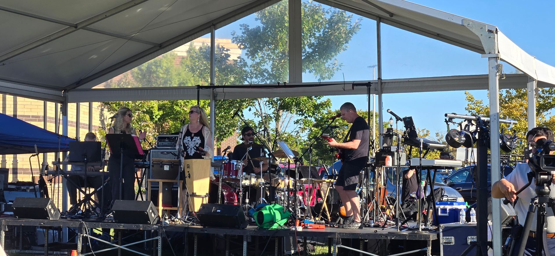A group of people are playing instruments on a stage under a tent.