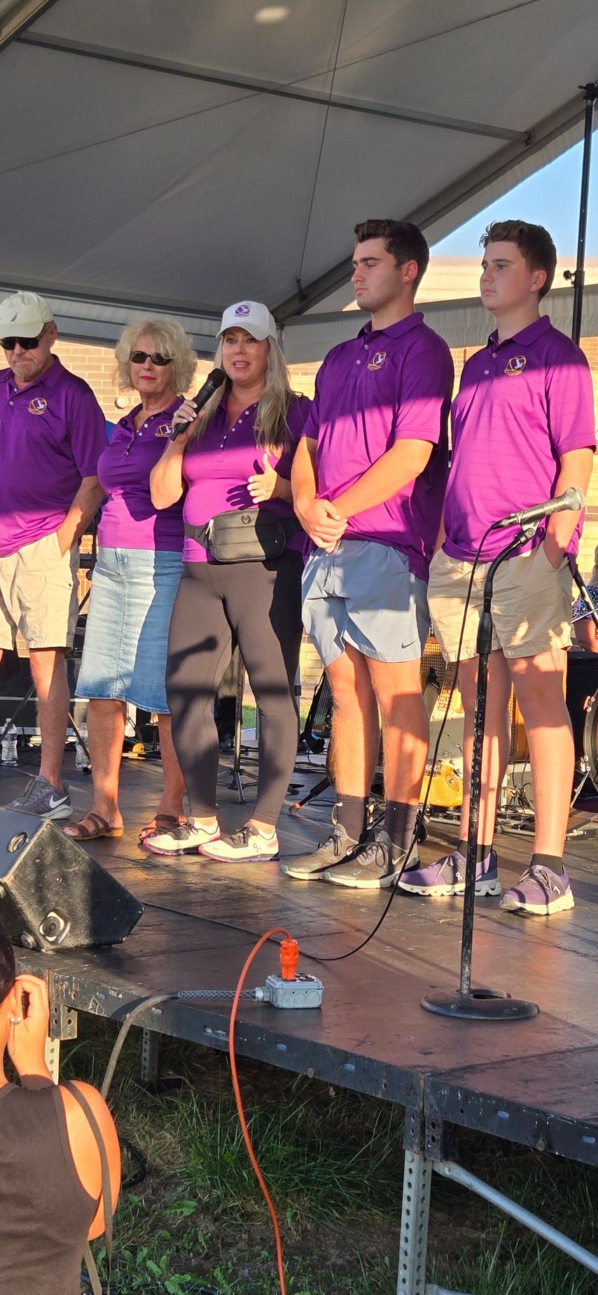 A group of people in purple shirts are standing on a stage.